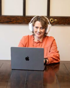 A woman sitting at a table with headphones on her head.